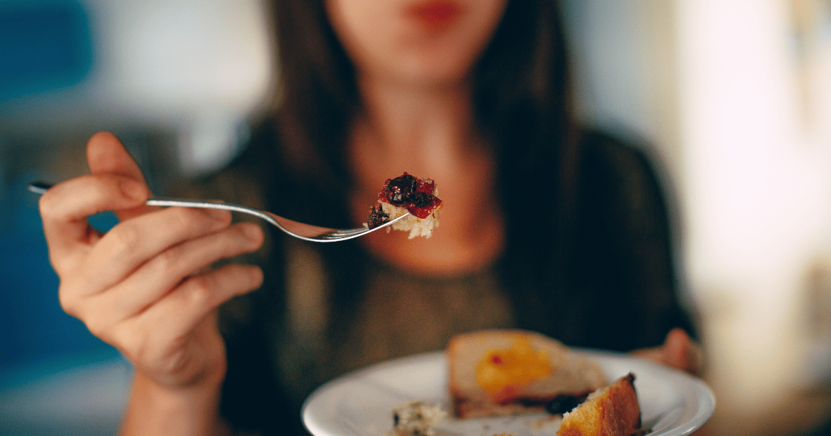 How to Eat Like a Food Writer shows a woman with a forkful of food.